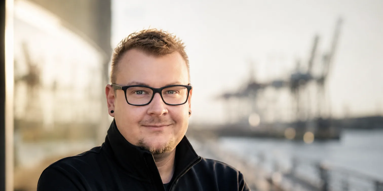 Porträt von Kevin Reymann, im Hintergrund die Containerbrücken des Hamburger Hafens